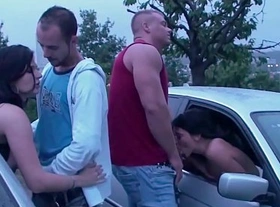 A girl is undressing in a car before joining a public sex orgy